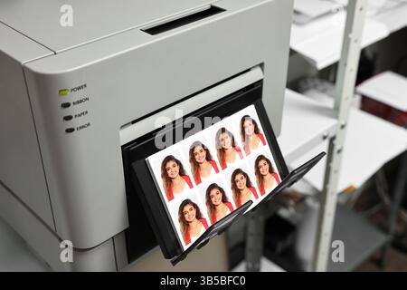 Imprimante moderne avec photos de passeport de femme à l'intérieur, gros plan Banque D'Images