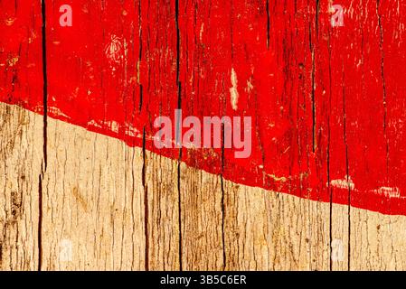 Gros plan de bois altéré avec une bande diagonale rouge audacieuse et une texture de grain vieilli, montrant un caractère rustique et un contraste visuel abstrait. Banque D'Images