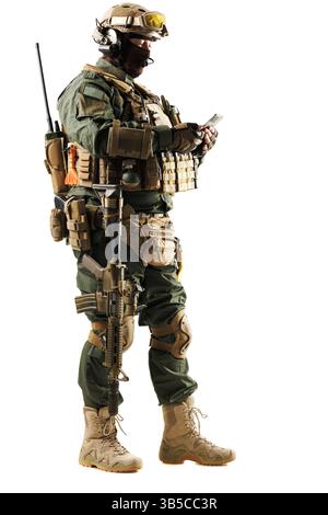 Un soldat lourdement équipé en équipement militaire utilisant un smartphone moderne, mettant l'accent sur la communication et la technologie en équipement de combat. Banque D'Images