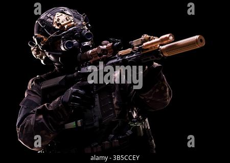 Un agent hautement équipé en équipement tactique vise une arme camouflée préparée pour une mission. La photo dépeint la technologie de pointe et la préparation Banque D'Images