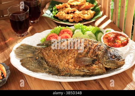 Ikan Gurame Goreng, Gourami frit servi avec une sauce épicée Sambal indonésienne, de la laitue et de la tomate Banque D'Images