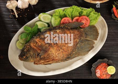 Vue de dessus Ikan Gurame Goreng, Gourami frit servi avec une sauce épicée Sambal indonésienne, de la laitue et de la tomate Banque D'Images