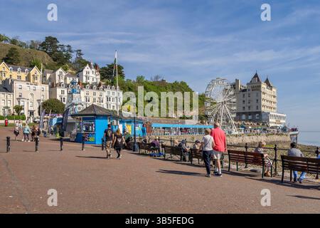 Llandudno Promenade avec la jetée, Grand Hôtel, Big Wheel, hôtels de bord de mer et les gens appréciant le temps chaud du printemps. Banque D'Images