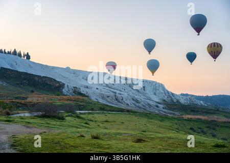 Montgolfières survolant les travertins de Pamukkale au lever du soleil Banque D'Images