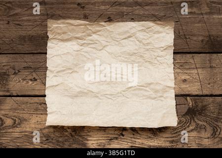 Vieille feuille de papier froissé sur une table en bois rustique, texture de fond vintage pour le texte, le menu, le modèle de conception ou la maquette rustique Banque D'Images