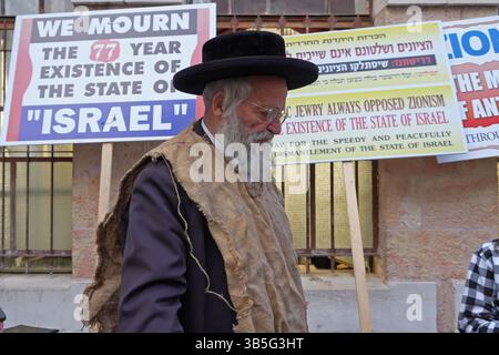 Un membre de Neturei Karta, un mouvement juif ultra-orthodoxe marginal au sein du bloc anti-sioniste porte un sac de jute pour signifier le chagrin alors qu'il dresse des signes contre le sionisme avant un rassemblement contre la création de l'État d'Israël lors de la 77e Journée de l'indépendance d'Israël le 1er mai 2025 à Jérusalem. Neturei Karta s'oppose au sionisme et appelle à un « démantèlement pacifique » de l'État d'Israël, dans la conviction qu'il est interdit aux Juifs d'avoir leur propre État jusqu'à la venue du Messie juif et que l'État d'Israël est une rébellion contre Dieu. Banque D'Images