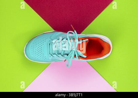 Rouge, cyan, blanc nouvelle chaussure de tennis en studio tourné sur fond vert, rose, violet. Directement d'en haut Banque D'Images