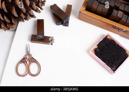 Timbres, tampon encreur, un petit ciseau et une pomme de pin sur une feuille de papier blanche dans une vue de dessus Banque D'Images