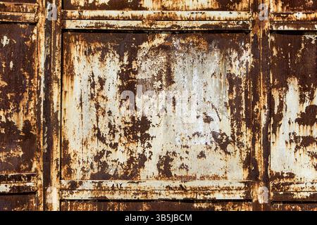 Gros plan d'un panneau métallique rouillé avec peinture écaillée et corrosion importante. Texture industrielle, surface âgée, fond abstrait, pas de personnes. Banque D'Images