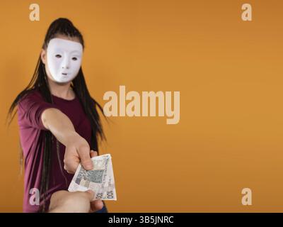Une femme anonyme se tient et tire sa main avec des billets en papier de la valeur nominale de cent zlotys polonais. Pas de visage car il y a un masque Banque D'Images