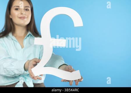 DAS Maedchen haelt ein grosses Pfund symbole dans ihren Haenden. Grossbritannien-Waehrungsform. Symbol fuer Finanzen und Cashflow in der Wirtschaft und d Banque D'Images