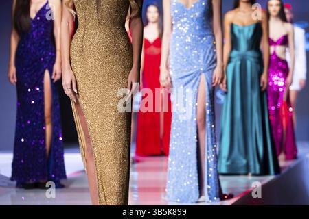 Les modèles féminins présentent une nouvelle création sur la piste de la collection automne / hiver pendant le défilé de la semaine de la mode. Robes colorées Banque D'Images