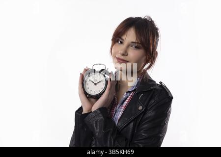 Une jeune femme confiante prend la pose avec un réveil mince, mettant en valeur son look très élégant et sa disponibilité Banque D'Images
