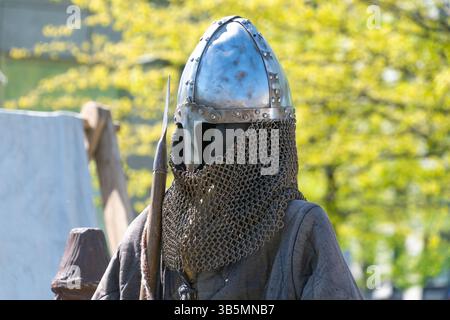 Chevalier médiéval en maille et casque tenant la lance à l'extérieur au printemps. Banque D'Images
