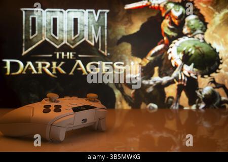 Dhaka, Bangladesh- 30 avril 2025 : gros plan d'une manette de jeu blanche avec le Doom the Dark Ages vu à l'écran en arrière-plan Banque D'Images