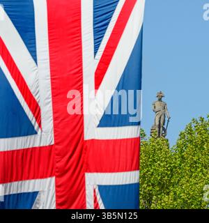 Londres, Royaume-Uni. La statue Nelson au sommet de la colonne Nelson à Trafalgar Square, vue de Whitehall, derrière un arbre et un drapeau de l'Union suspendu à l'extérieur Banque D'Images