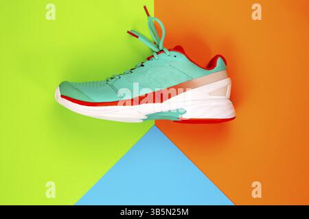 Rouge, cyan, blanc nouvelle chaussure de tennis en studio tourné sur fond vert, orange, bleu. Directement d'en haut Banque D'Images