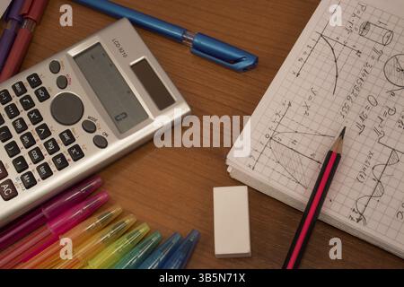 Crayons colorés, calculatrice, gomme et cahier sur la table Banque D'Images