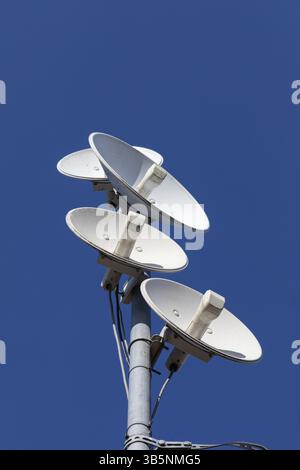 Antennes de télécommunications blanches sur un seul mât haut au-dessus de la ville sur le fond d'un ciel bleu. Technologie d'envoi numérique et de réception Banque D'Images