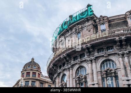 Gênes, Italie - 22 septembre 2024 : le bâtiment historique de la Banca Carige avec des enseignes au néon et une façade ornée surplombe la Piazza de Ferrari, la principale place de la ville Banque D'Images