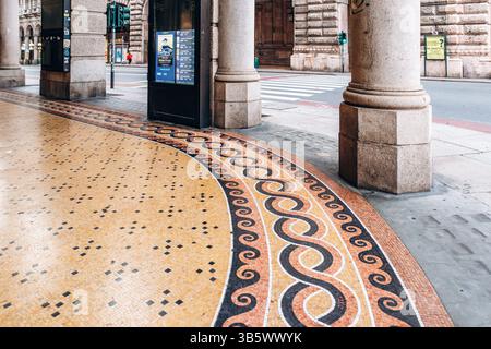 Gênes, Italie - 22 septembre 2024 : sol en mosaïque colorée sous de hautes arcades en pierre le long de la via XX Settembre, la principale rue commerçante de Gênes. Banque D'Images