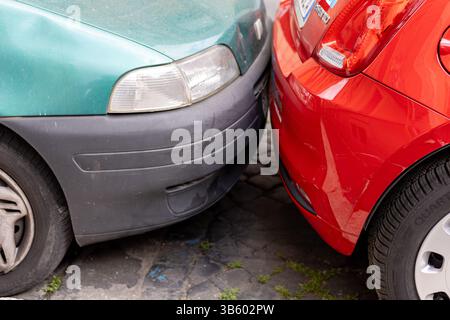 ROM, Italien - 24 avril 2025 : deux voitures sont garées très près l'une de l'autre dans une rue pavée. Leurs pare-chocs se touchent, mettant en évidence le par serré Banque D'Images