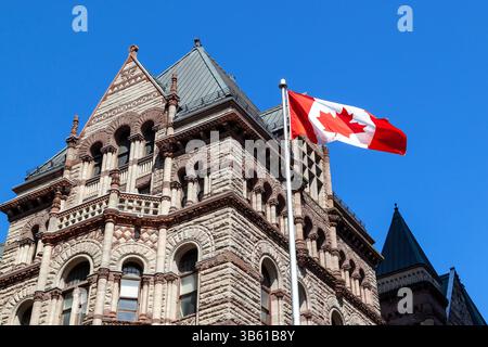 Toronto, Canada - 16 mai 2020 : drapeau canadien agitant avec l'ancien hôtel de ville en arrière-plan à Toronto, Canada. Banque D'Images