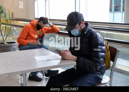 9 avril 2022, SeaTac, Washington, États-Unis : les bénévoles utilisent leur téléphone cellulaire en attendant qu'une simulation de flux de passagers commence à l'installation des arrivées internationales de l'aéroport international Seattle-Tacoma à SeaTac, Washington, le samedi 9 avril 2022. La nouvelle installation de 450 000 pieds carrés du Port de Seattleâ™devrait ouvrir le mois prochain après la fin des tests finaux de préparation opérationnelle. (Crédit image : © Paul Christian Gordon/ZUMA Press Wire) Banque D'Images