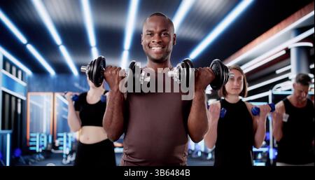 Classe de fitness en groupe dans le gymnase : diverses personnes soulevant des poids ensemble. Banque D'Images