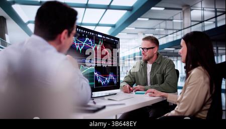 Analystes financiers analyser les graphiques boursiers sur les écrans d'ordinateur dans Office Setting. Banque D'Images