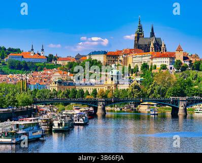 Vue panoramique du château de Prague avec des bateaux sur la rivière Vltava. Paysage urbain captivant avec architecture historique et voies navigables animées pour le voyage Banque D'Images