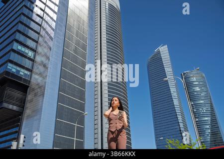 Femme d'affaires utilisant smartphone dans le quartier d'affaires cuatro torres, madrid, espagne Banque D'Images
