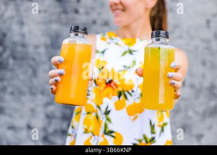 Plan au-dessus de la tête des mains de la femme tenant des bouteilles de jus de fruits et de légumes Banque D'Images