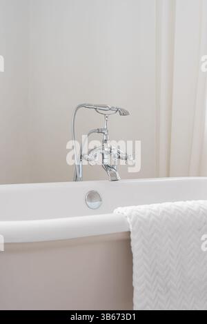 Robinet en métal chromé brillant sur baignoire autoportante blanche. Appareil de plomberie, élément de salle de bain, design d'intérieur, robinet d'eau élégant Banque D'Images