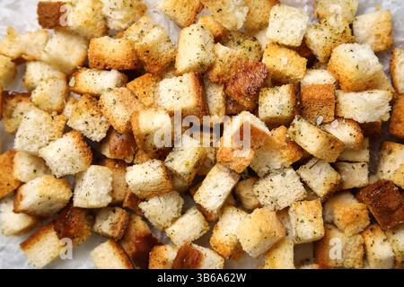 Croûtons croquants avec des épices sur papier cuisson, gros plan Banque D'Images