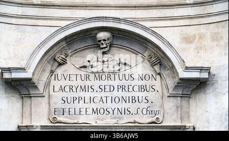 Inscription en pierre représentant un crâne et des os croisés, avec texte latin. Le dessin est orné, placé sur un fond de pierre texturé, transportant un sombe Banque D'Images