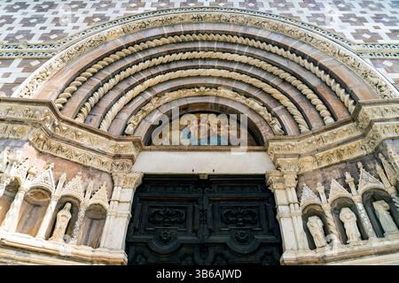 Une vue détaillée d'une entrée architecturale ornée avec des sculptures en pierre complexes, une grande porte en bois et une fresque au-dessus de l'arche. Le desig Banque D'Images
