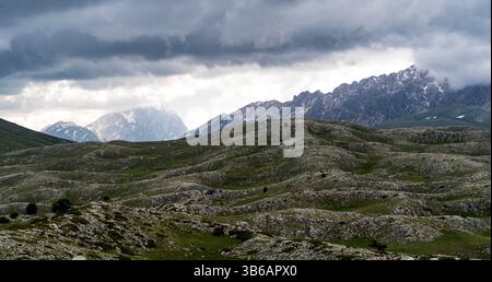 Un paysage spectaculaire avec des collines ondoyantes et des montagnes escarpées sous un ciel nuageux. La scène capture la beauté de la nature avec un mélange de verdure A. Banque D'Images