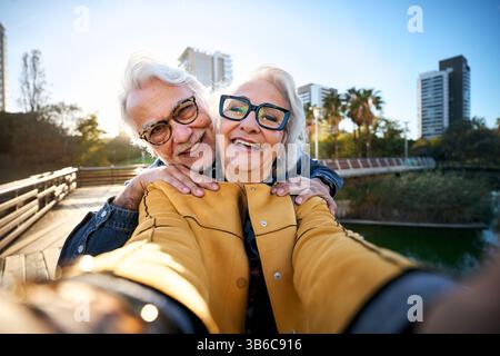 Heureux couple senior prenant un selfie dans le parc de la ville Banque D'Images