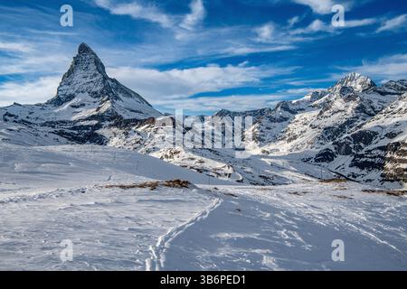 L'emblématique Cervin domine majestueusement les Alpes enneigées, son sommet pointu qui pénètre dans le ciel bleu, une scène hivernale à couper le souffle Banque D'Images