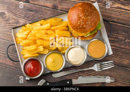Hamburger écrasé avec des oignons croustillants servi avec des frites et des sauces Banque D'Images