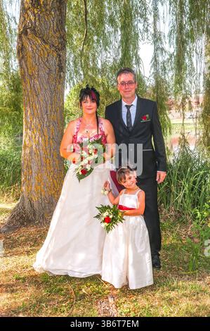 Mariée, mariée et demoiselle d'honneur posent pour des photographies de mariage dans un jardin public local - Preuilly-sur-Claise, Indre-et-Loire (37), France. Banque D'Images