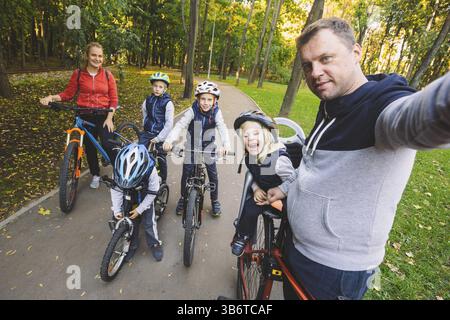 Le thème famille sports loisirs de plein air. grande famille 6 personnes de race blanche Papa maman et 4 enfants trois frères et soeur de la bicyclette dans le parc Banque D'Images