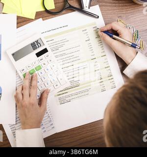 Gros plan d'une main féminine calculant, sur le bureau Banque D'Images