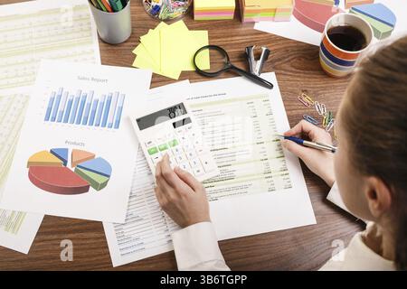 Gros plan d'une main féminine calculant, sur le bureau Banque D'Images