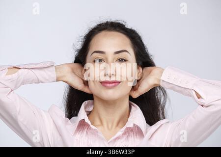 Portrait d'une belle fille brune à la peau foncée dans un chandail rose, avec une expression grave. Voir l'émotion est arrogant avec hauteur. Businesswoman por Banque D'Images