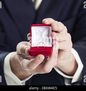 Gros plan de l'homme tenant la bague de mariage et la boîte cadeau Banque D'Images