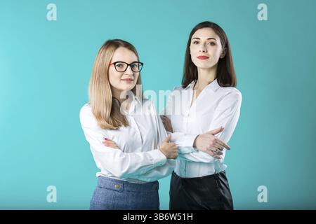 Le thème est une équipe féminine. portrait de deux jeunes femmes d'affaires caucasiennes posant en studio sur un fond coloré. Travail d'équipe deux personnes dans le bureau cl Banque D'Images