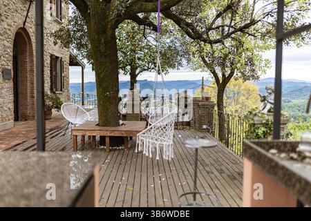 Chaise balançoire relaxante suspendue à un chêne vert sur une terrasse panoramique surplombant les collines toscanes Banque D'Images