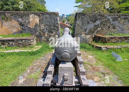 Vieux canon à Galle Fort pointant vers l'océan sous le ciel bleu et les palmiers en été Banque D'Images